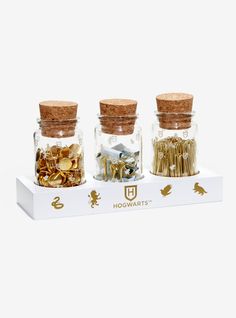 three glass jars filled with different types of screws and nuts on top of a white box