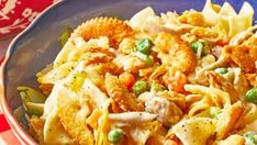 a blue bowl filled with pasta and vegetables on top of a red table cloth next to a fork