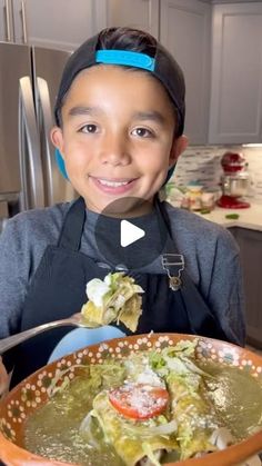 a young boy holding a bowl of food in front of him and smiling at the camera