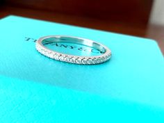 a diamond wedding band sitting on top of a blue box with the name tiffany written on it