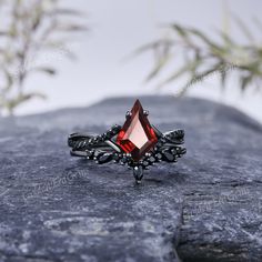 a red stone ring sitting on top of a rock