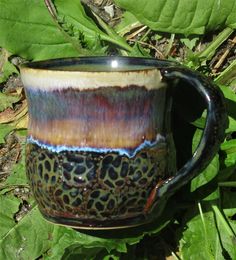 a close up of a coffee cup on the ground near some grass and plants with green leaves