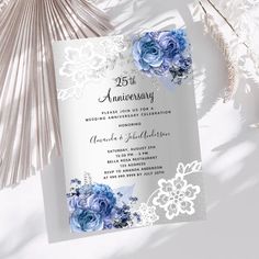 an elegant wedding card with blue flowers and lace on the edge, next to a fan