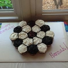 a cupcake with white frosting and black icing is on top of a card board