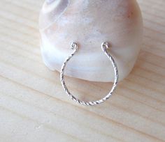 a silver ring sitting on top of a wooden table next to a white rock and sea shell