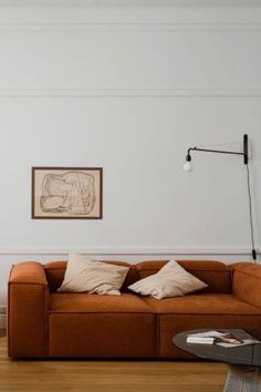 a living room with a couch, table and lamp on the wall next to it