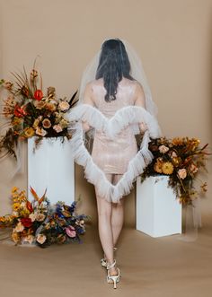 a woman in a wedding dress is standing next to two vases with flowers on them