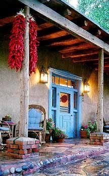 a blue front door with red peppers hanging from it's roof and brick walkway