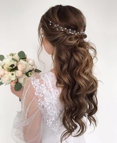 a woman with long hair holding flowers in her hand and wearing a tiara on her head