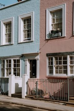 two multi - colored buildings with white windows and iron railings