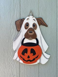 a dog with a jack o lantern on it's head hanging from a door