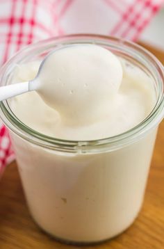 a glass jar filled with yogurt sitting on top of a wooden table