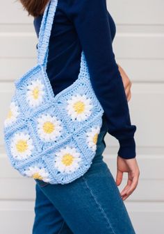 a woman carrying a crocheted blue and white bag with yellow flowers on it