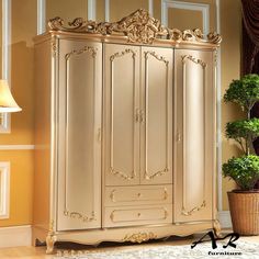 an ornately decorated armoire stands next to a potted plant in a living room