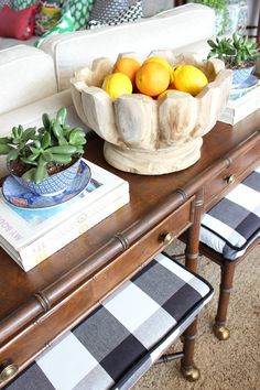 a bowl of lemons sitting on top of a wooden table next to a couch