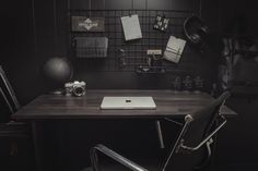 a laptop computer sitting on top of a wooden desk next to a chair and wall