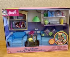 the barbie doll house has two blue couches and a table with a lamp on it