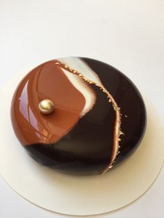 a chocolate cake with white and brown icing on it's side sitting on a plate