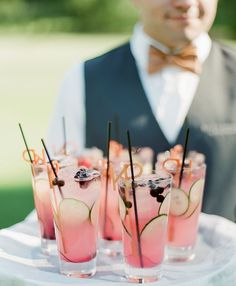 several glasses filled with drinks sitting on top of a white table covered in fruit and veggies