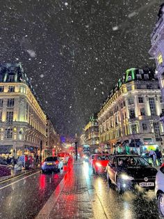 cars are driving down the street on a snowy night in paris, with snow falling from the sky