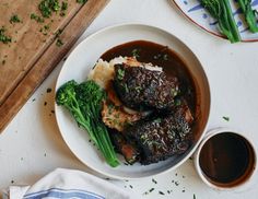 some meat and broccoli on a plate with gravy next to it