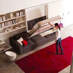 a woman standing on top of a red rug in front of a living room filled with furniture