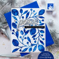 a close up of a card with blue leaves and snowflakes in the background