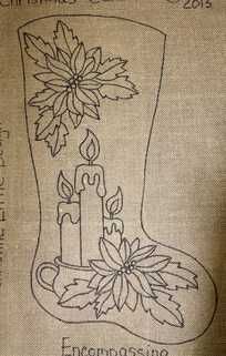 an embroidered christmas stocking with candles and poinsettis on the boot is shown