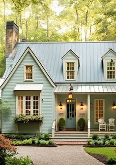 a blue house with white trim and lots of windows on the front door, surrounded by greenery