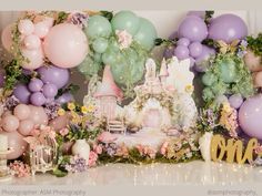 a backdrop with balloons, flowers and a castle