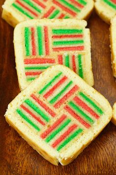 several small pieces of cake with red, green and white frosting on them sitting on a wooden surface