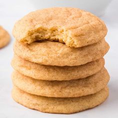 a stack of cookies with one bite taken out of the middle and another cookie in the background