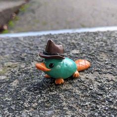 a toy bird with a hat on its head sitting in the middle of a road