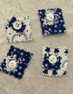 four pieces of blue and white fabric with snowflakes on them, one has a button in the middle