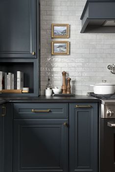 a kitchen with dark blue cabinets and white brick backsplash, brass pulls on the cabinet doors