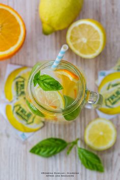 there is a glass with lemonade and mint on the table next to sliced lemons