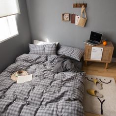 an unmade bed in a bedroom with grey walls