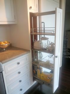 an open cabinet in a kitchen with white cabinets