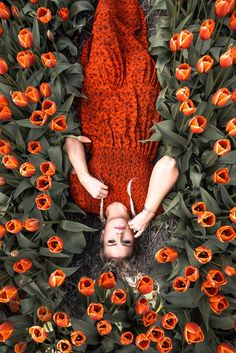 a woman laying down in the middle of flowers