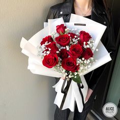 a woman holding a bouquet of red roses