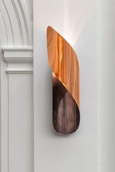 a wall mounted light on the side of a white wall next to a doorway with an arch