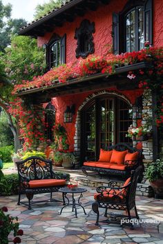 an outdoor patio with red flowers and furniture