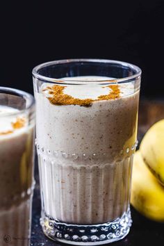 two glasses filled with food sitting on top of a table next to banana's