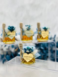 four small bottles filled with honey on top of a clear table covered in blue and white decorations