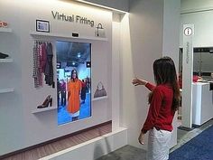 a woman pointing at a virtual fitting display