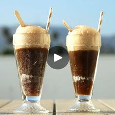 two glasses filled with ice cream and chocolate milkshakes sitting on top of a wooden table