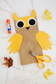 a paper bag with an owl cut out on it and some scissors next to it