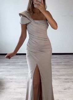 a woman taking a selfie wearing a dress with one leg slited in front