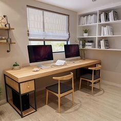 two computer monitors sitting on top of a wooden desk in front of a book shelf