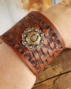 This gorgeous leather cuff bracelet is basket stamped with a beautiful horse shoe concho added.  The cuff is 2" wide and snaps closed fitting up to an 8 inch wrist. If you have a small wrist and would like us to add an additional snap, please let us know. Hand Tooled Brown Jewelry For Rodeo, Brown Hand Tooled Jewelry For Rodeo, Vintage Leather Bracelet With Concho, Vintage Brown Jewelry For Rodeo, Vintage Hand-tooled Cuff Jewelry, Handmade Western Style Cuff Bracelets, Brown Hand Tooled Western Bracelets, Hand Tooled Brown Cuff Jewelry, Handmade Leather Western Cuff Bracelet